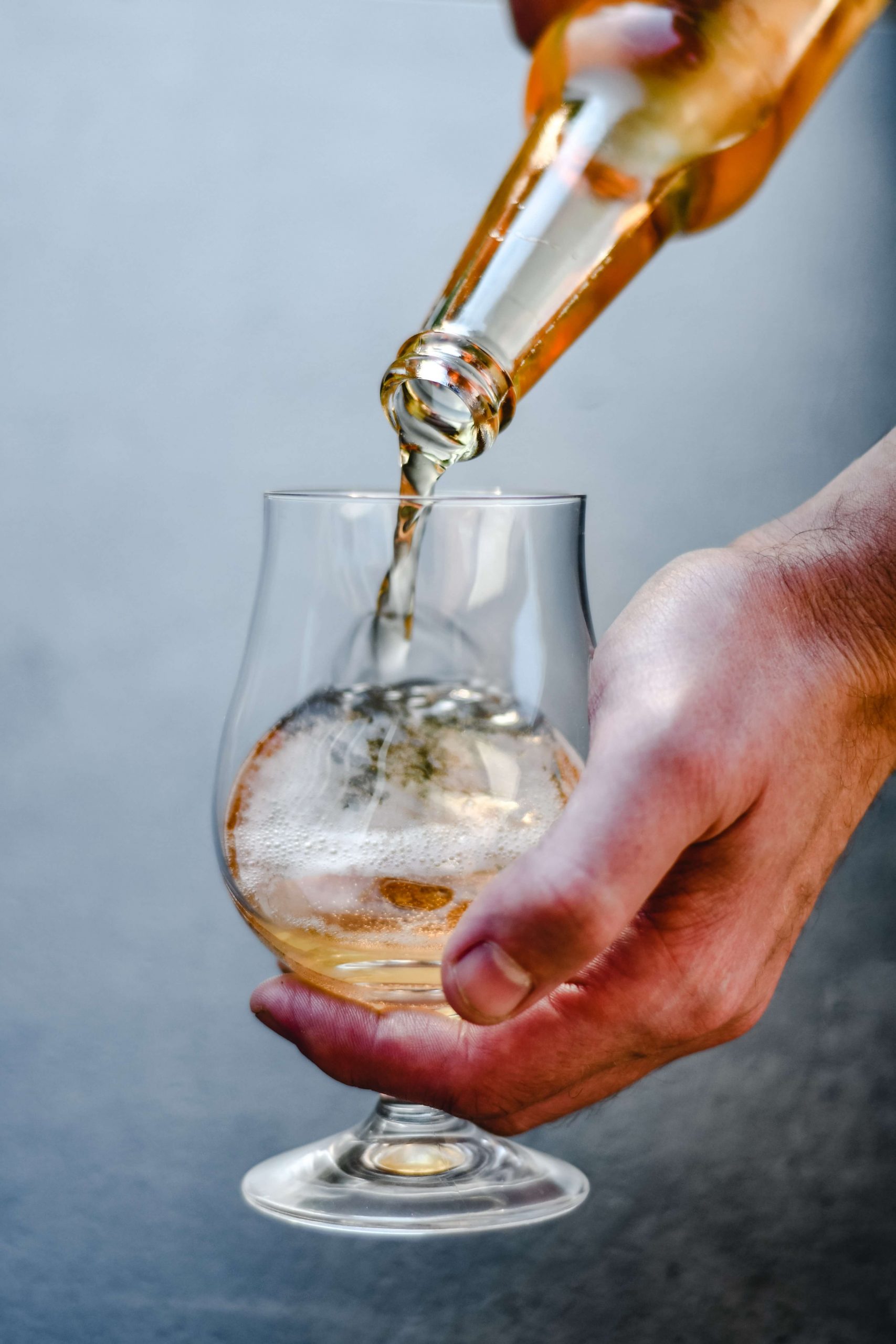 A person pouring a bottle of whiskey into a glass.