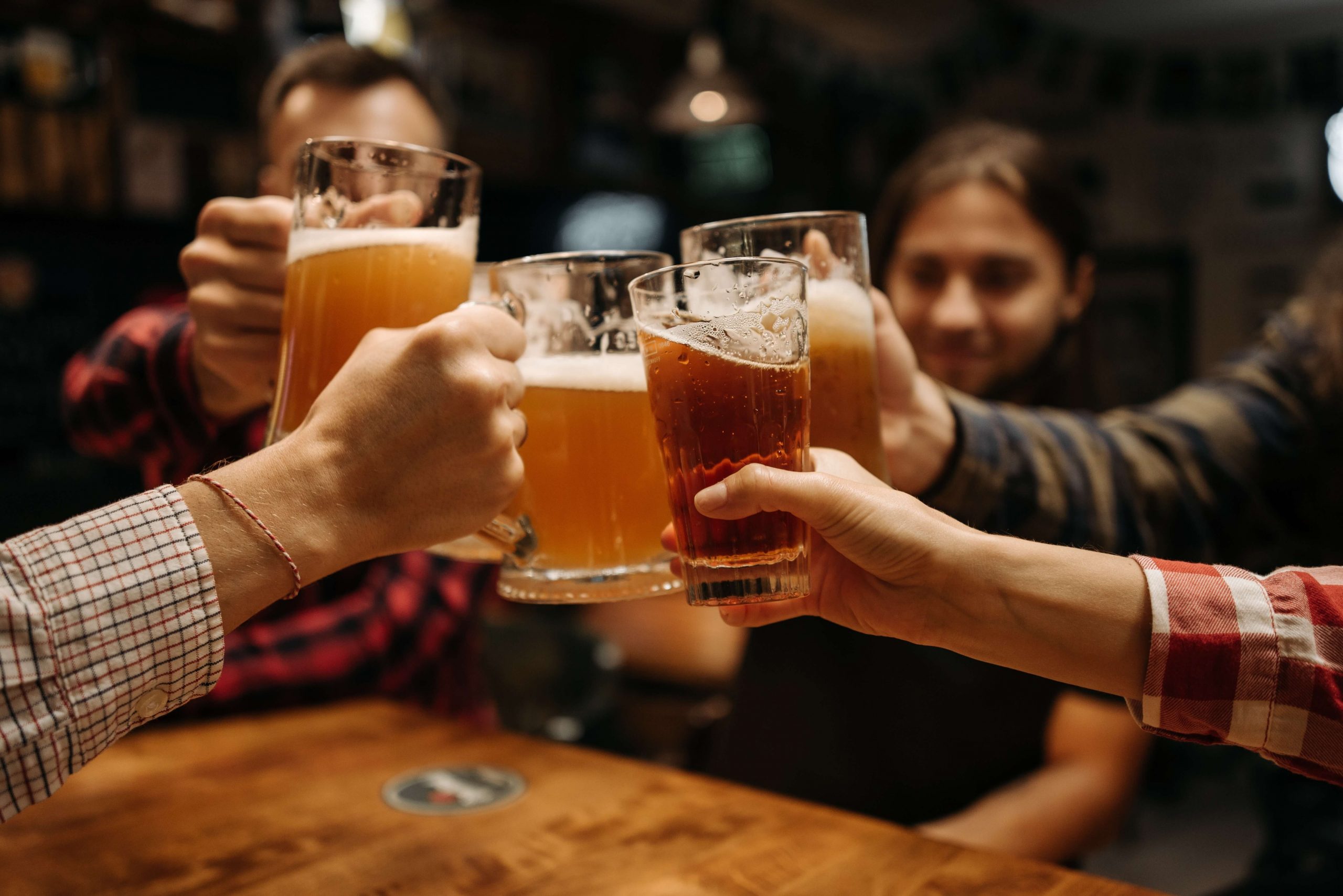 A group of people toasting beer glasses at a bar.