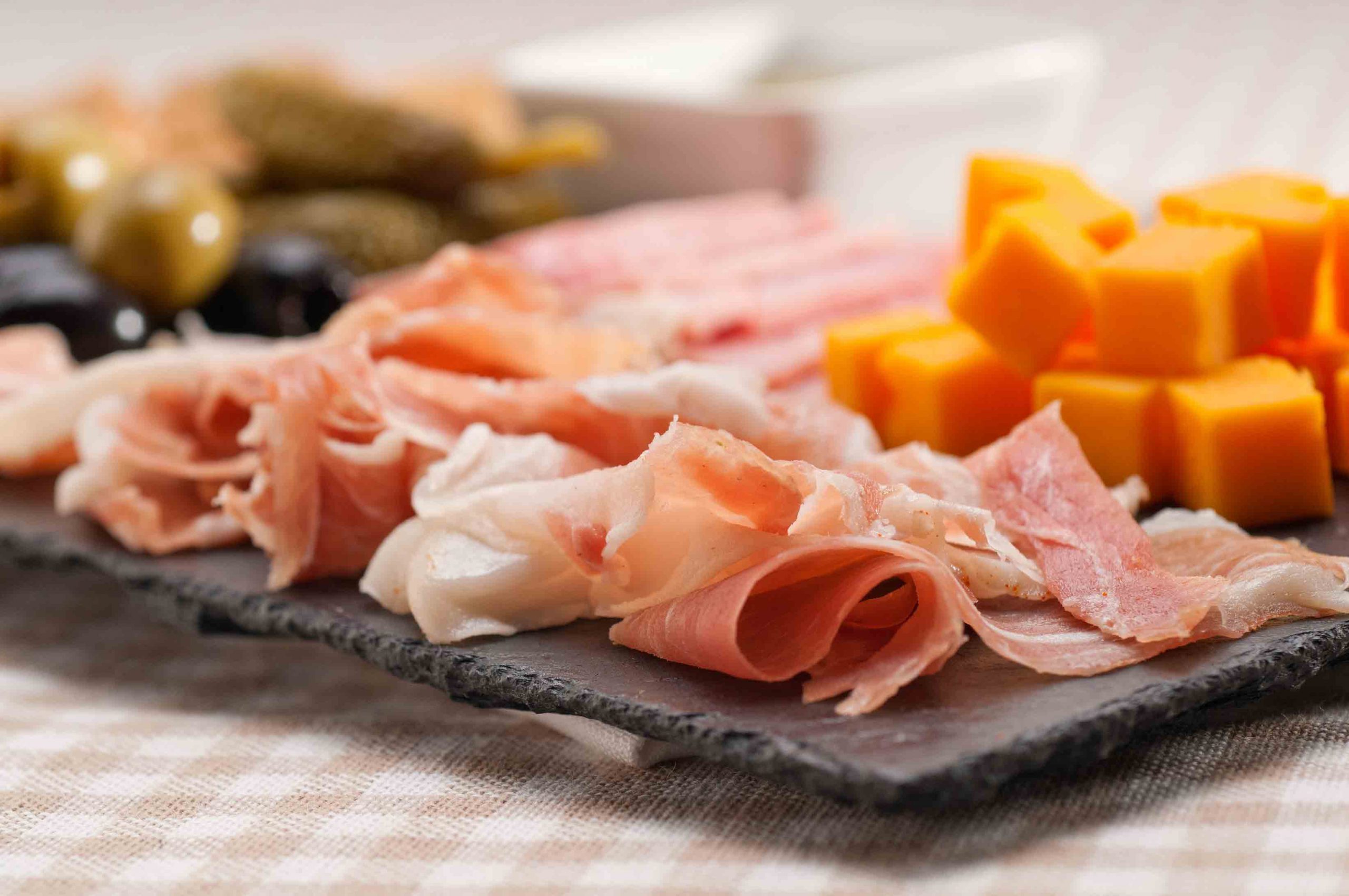 A platter with ham, cheese, olives and pickles.